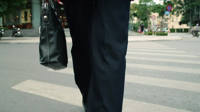Close up rear view of a hurry aucasian middle aged business man in leather shoes and suit on the way to the office building,businessman in a suit crosses the road on a zebra crossing, man gets to work
