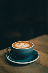 Cup of Coffee with latte art served on wood table.
