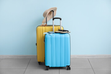 Packed suitcases with immune passport, medical masks and beach accessories near color wall