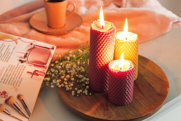 Burning candles, cup of coffee and magazine on table