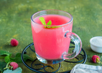 Traditional Russian hot drink raspberry jelly or kissel in a glass transparent mug on a green concrete background.