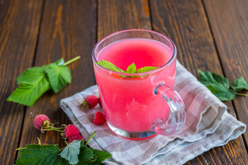 Traditional Russian hot drink raspberry jelly or kissel in a glass transparent mug on a brown wooden background.