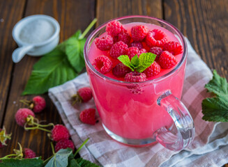 Traditional Russian hot drink raspberry jelly or kissel in a glass transparent mug on a brown wooden background.