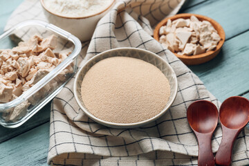 Bowls with fresh and dry yeast on color wooden background