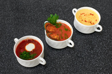 Three different types of soups: borsch with sour cream, tomato soup with mussels, creamy soup