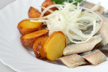Pieces of salted herring fillet with baked potatoes and onions