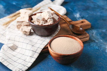 Bowls with fresh and dry yeast on color background