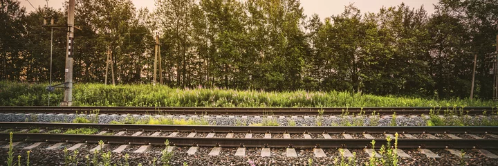 Poster Leere lange Eisenbahnstrecke gegen grüne Bäume Seitenansicht © Bonsales