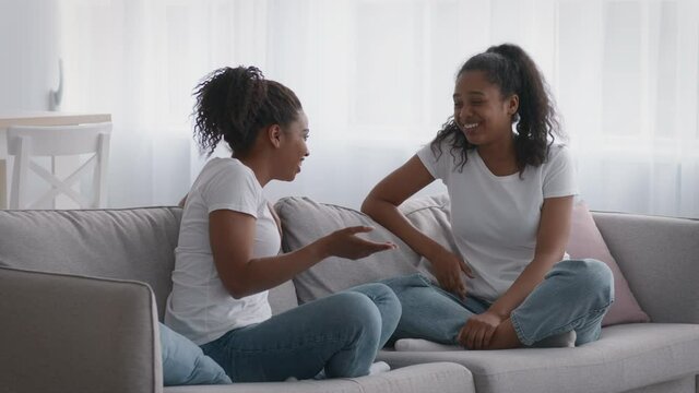 Happy sisterhood and great family relationships. Positive teen and adult african american sisters talking at home