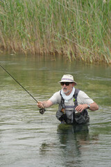 fly fisherman fishing in a small wild river