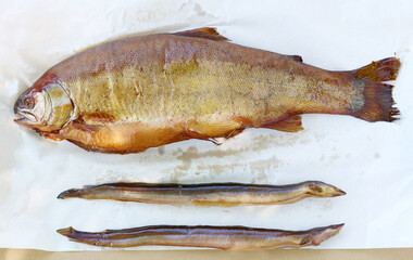 Smoked trout and eels lie on white paper