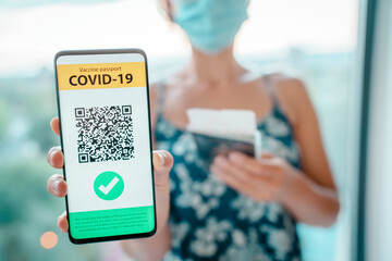 COVID-19 Vaccine passport on mobile phone app screen woman tourist showing vaccination proof at...