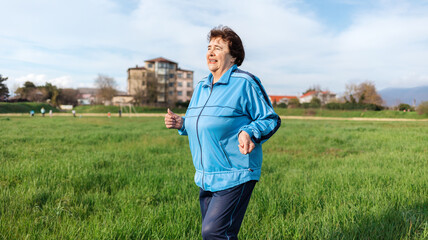 Running and sports activity. Portrait of mature smiling grandmother in sports clothes runs through...