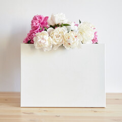 Obraz na płótnie Canvas Canvas mockup with pink flowers on wooden table on white wall background