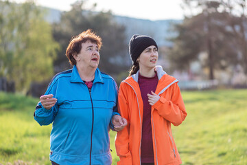 Naklejka premium Family outdoor vacation. Portraits of grandmother and granddaughter walking together in the spring park. International Day of Older Persons