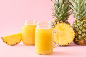 Mason jars of tasty pineapple smoothie on color background