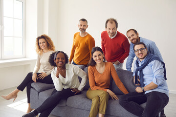 Diverse people group of different age and ethnicity sitting on sofa couch in office posing and...