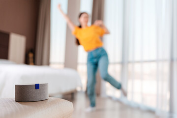 A portable smart gray speaker plays music. In the background, a woman dances in a blur. The concept...