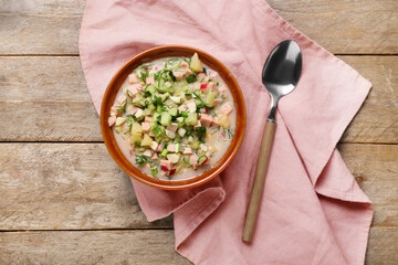 Bowl with tasty okroshka on wooden background