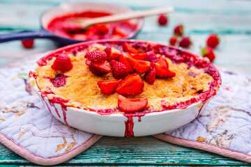 Delicious crumble with fresh strawberry fruit on a wooden background.