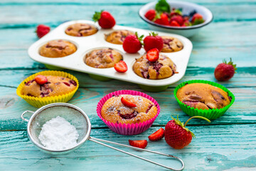 Delicious muffins with fresh strawberry fruit on a wooden background.