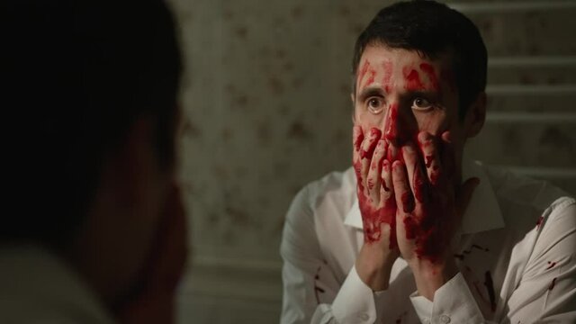 Maniac rubs blood across his face
