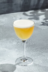 Whisky Sour Cocktail is a whiskey based cocktail with egg white. Vintage table with sunshine and shadow. Strong alcohol drink with whisky, sugar syrup and lemon juice.