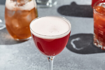 Red Martini Sour Cocktail is a martini based cocktail topped with egg white. Vintage table with...