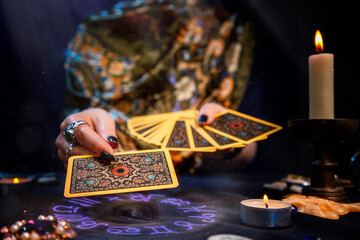The fortune teller holds a fan of cards in her hands and holds out a card with one hand. The...