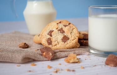 Delicious homemade chocolate chip cookies, paired with fresh milk in a glass and pitcher, placed on a white wooden floor and a blue background cloth. Drink in the morning for health and strong bones.