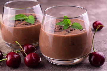 Chocolate cherry smoothie in a glass on a gray background.
Close-up.