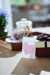 heart shape greeting card  with gift box and teaset on wooden table