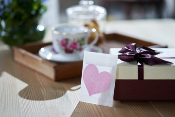 heart shape greeting card  with gift box and teaset on wooden table