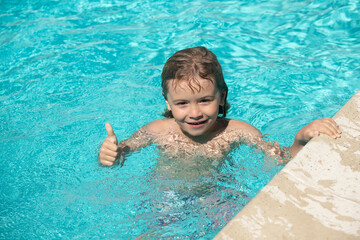 Fototapeta na wymiar Child boy with thumbs up swim in swimming pool.