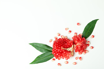 Ripe pomegranate with leaves on white background