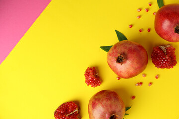 Ripe pomegranate, leaves and seeds on yellow background