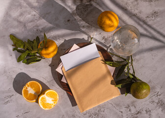Sliced orange fruits with leaves, blank card on white table background in sunlight. Close up mock...