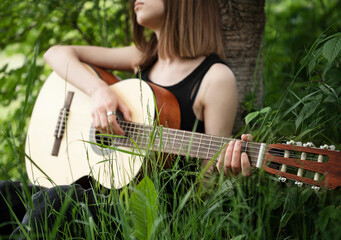 Teenager girl playing guitar in park