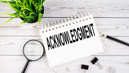 ACKNOWLEDGMENT text concept write on notebook with office tools on wooden background