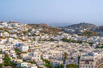 Fototapeta na wymiar Beautiful view of Chora town of Mykonos at sunset, Greece. Whitewashed houses, hills, greenery, seafront, famous windmills. 