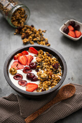Granola mit Joghurt und firschen Erdbeeren in einer Schüssel auf einem rustikalen Tisch. Nahaufnahme, gesundes Frühstück.