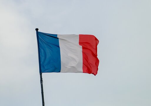 Bandera de Francia en Oloron-Sainte-Marie contra un cielo blanco nublado. Bandera ondeando en el viento.