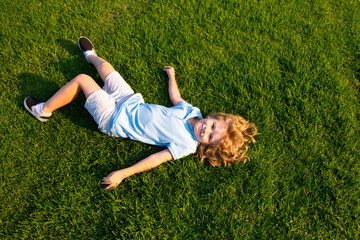 Happy smiling boy relaxing on the grass. Top view with copy space.