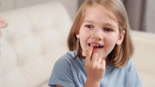 Little girl shows mother reeling tooth. changing milk teeth to indigenous teeth.