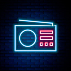 Glowing neon line Radio with antenna icon isolated on brick wall background. Colorful outline concept. Vector