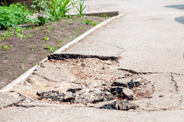 damaged broken asphalt, a hole on the sidewalk
