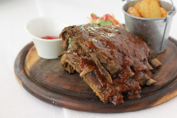 Grilled and smoked ribs with barbeque sauce on a carving board