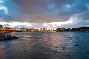 Miami, Florida cityscape skyline on Biscayne Bay. Panorama at dusk with urban skyscrapers and bridge over sea with reflection.