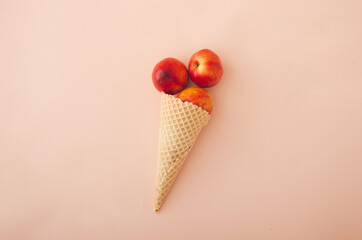Ice cream waffle cone with peaches inside on pink background. Minimal summer concept.