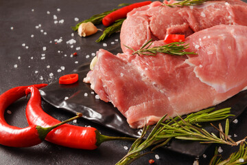 pork  tenderloin with chili pepper, rosemary on a blac